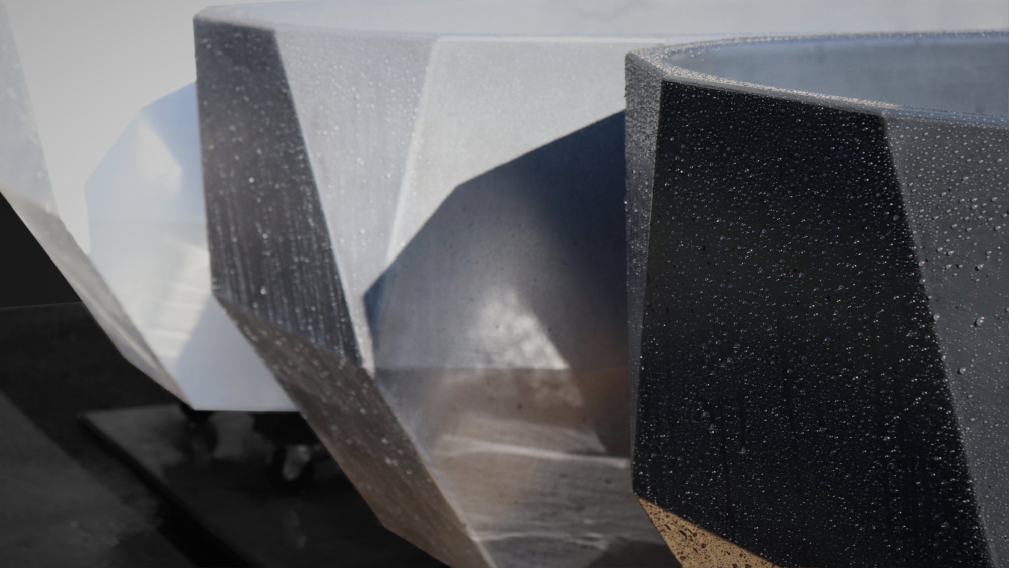 
                  
                   Three SpaCrete Geometric concrete bathtubs viewed close-up at 45-degree angle in titanium white, charcoal and industrial grey
                  
                